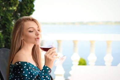 Photo of Beautiful woman drinking glass of wine on restaurant terrace