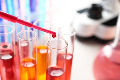 Photo of Dripping reagent into test tube with sample in chemistry laboratory, closeup. Space for text