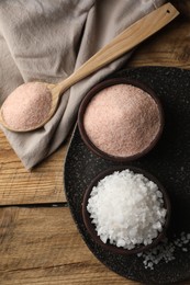 Photo of Different natural salt on wooden table, flat lay