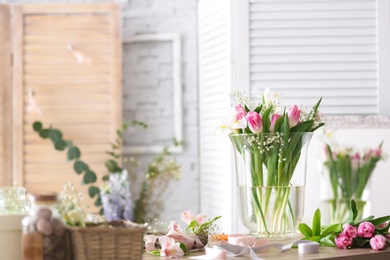 Photo of Decorator's workplace with beautiful flowers on table