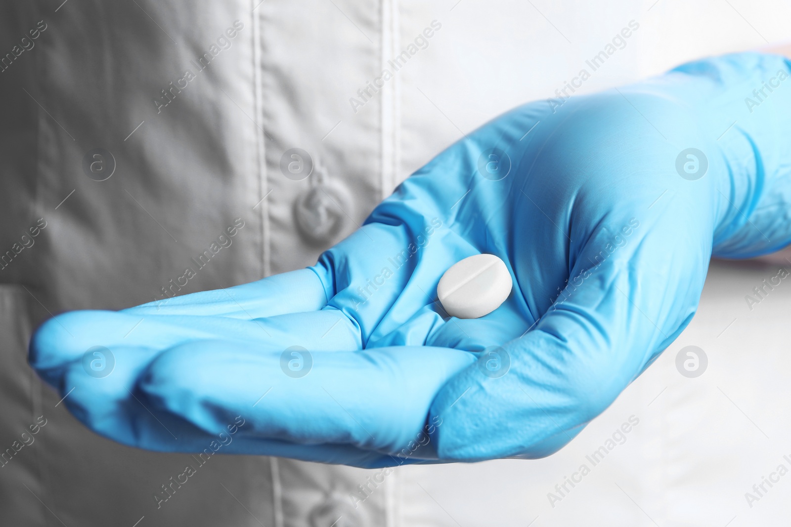 Photo of Doctor in medical glove holding pill, closeup view