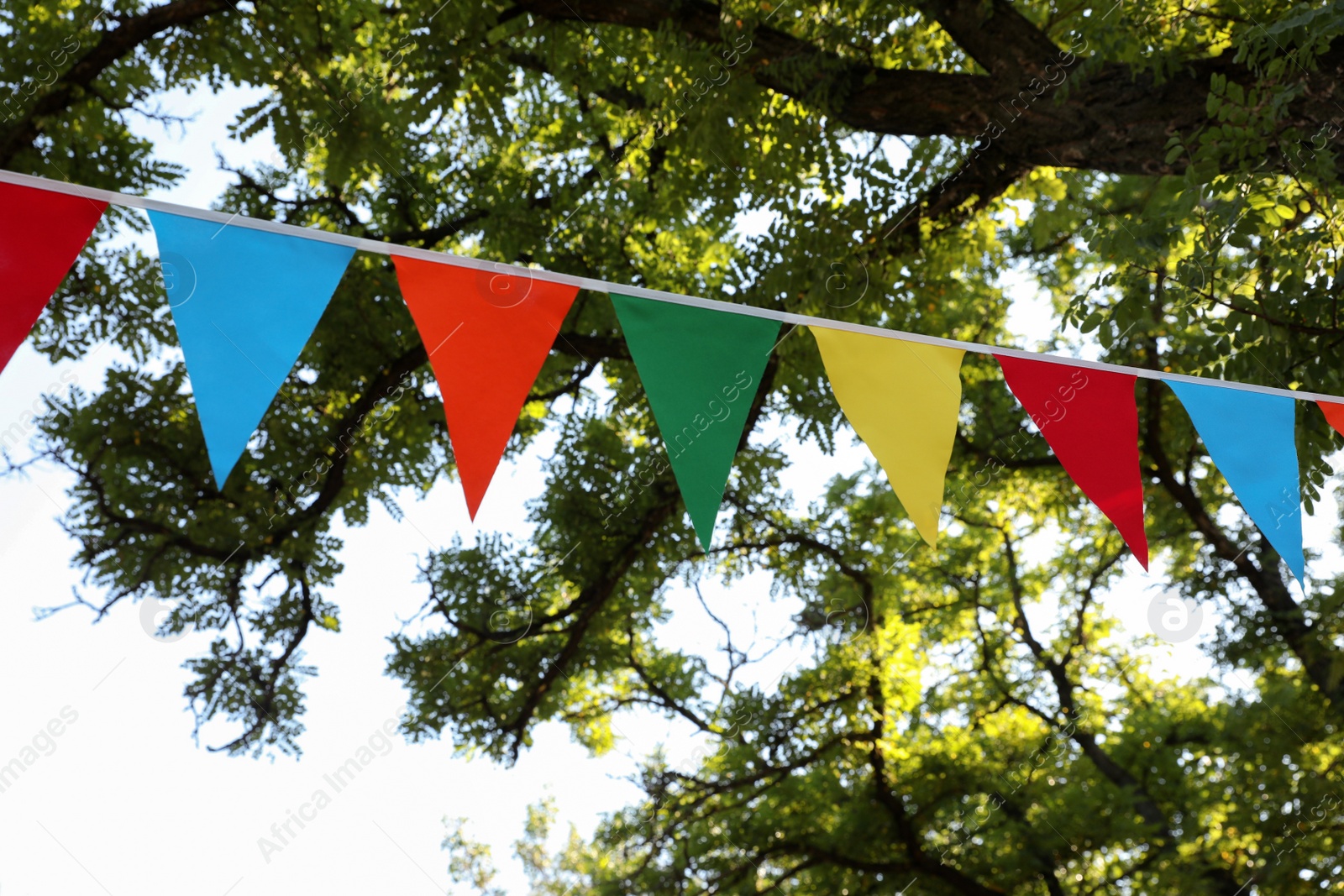 Photo of Colorful bunting flags in park. Party decor