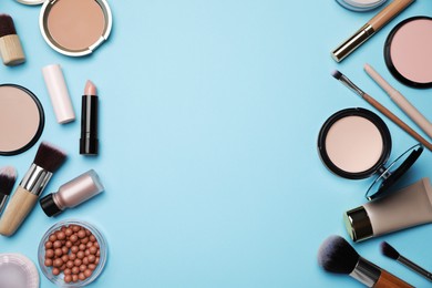 Face powders and other decorative cosmetic products on light blue background, flat lay. Space for text