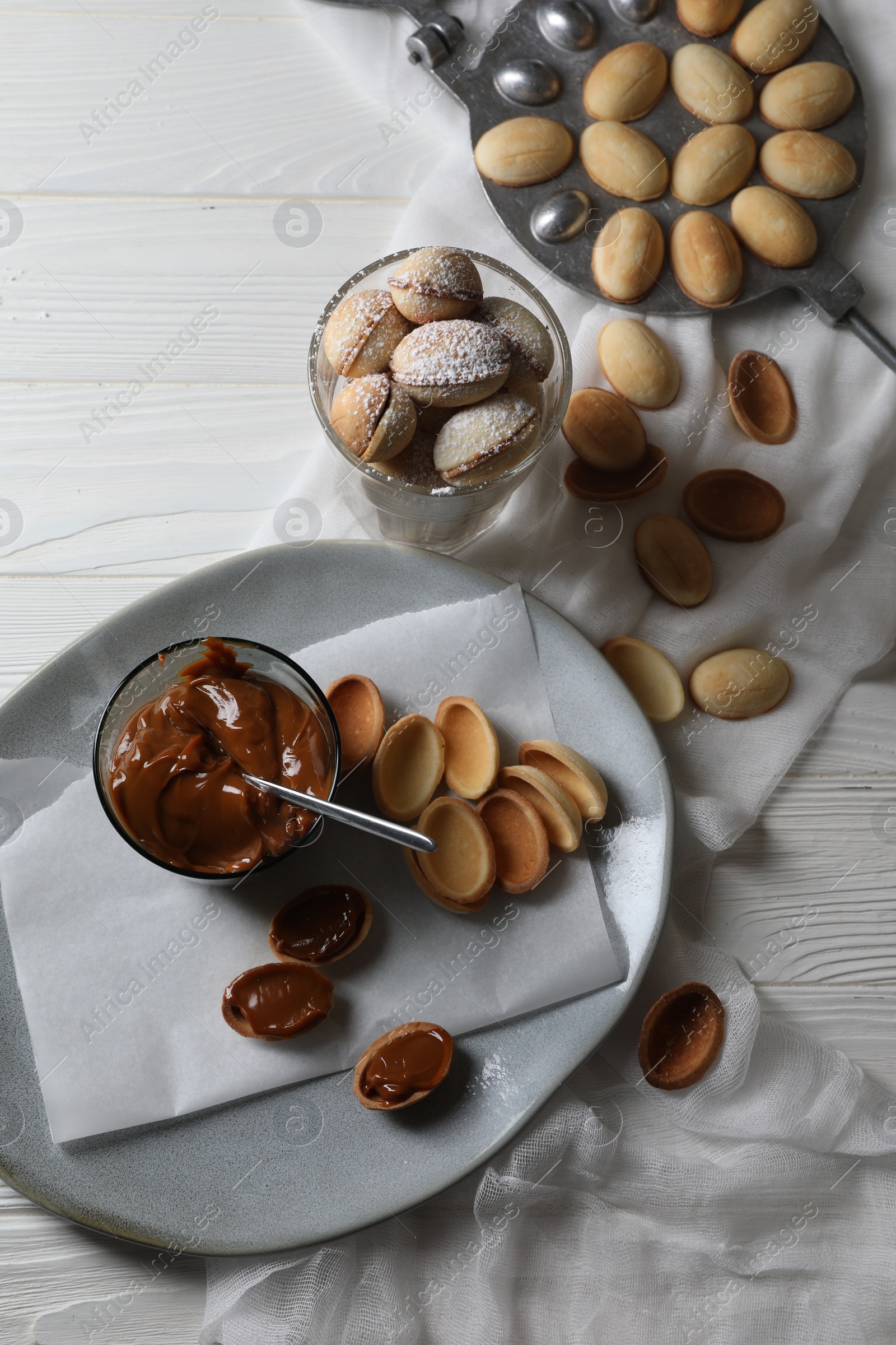 Photo of Delicious walnut shaped cookies with condensed milk on white wooden table, flat lay