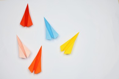 Handmade colorful paper planes on white table, flat lay. Space for text