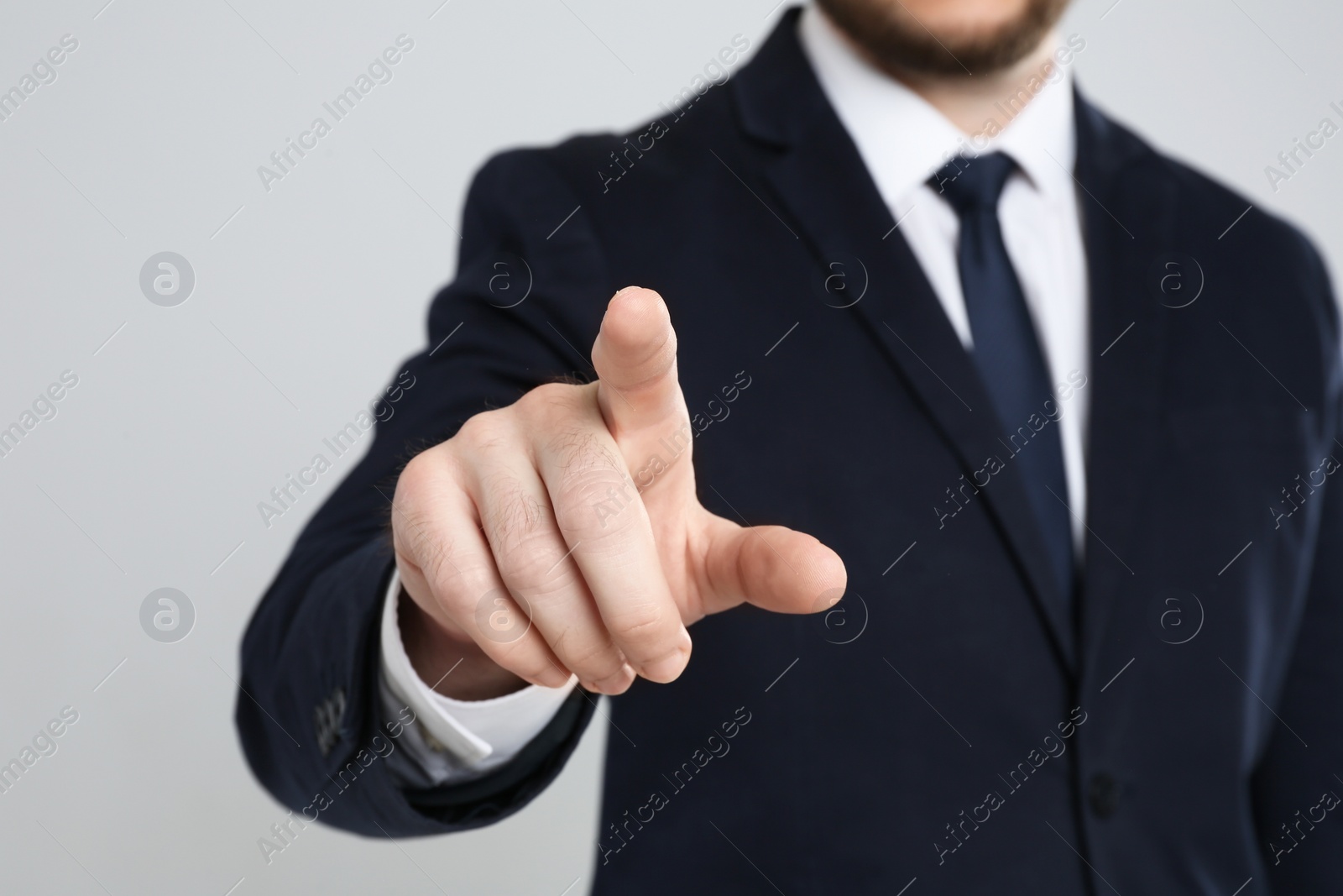 Photo of Businessman touching something against grey background, focus on hand