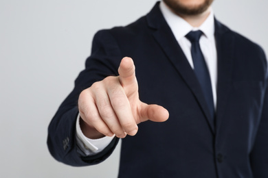 Photo of Businessman touching something against grey background, focus on hand