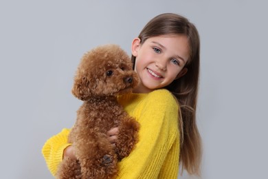 Photo of Little child with cute puppy on light grey background. Lovely pet