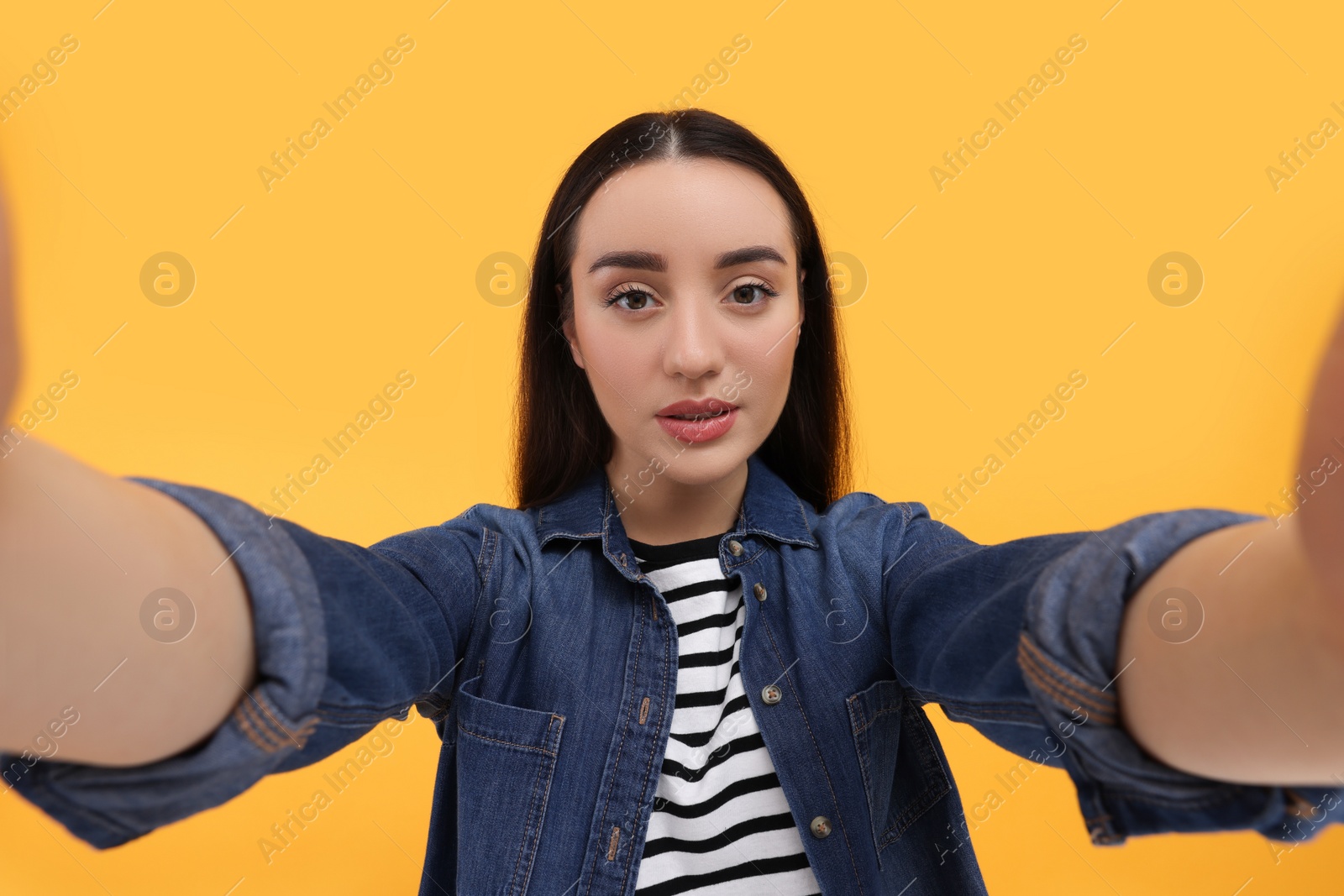 Photo of Young woman taking selfie on yellow background