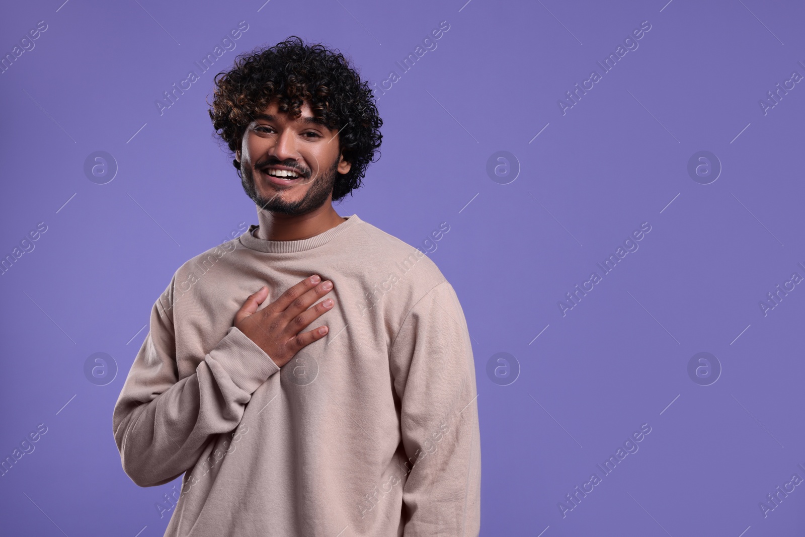 Photo of Handsome smiling man on violet background, space for text