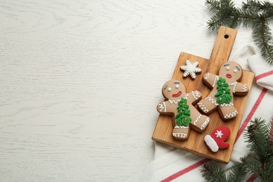 Delicious Christmas cookies and fir branches on white wooden table, flat lay. Space for text