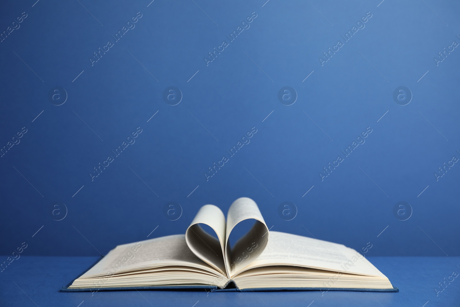 Photo of Open old hardcover book on blue background. Space for text