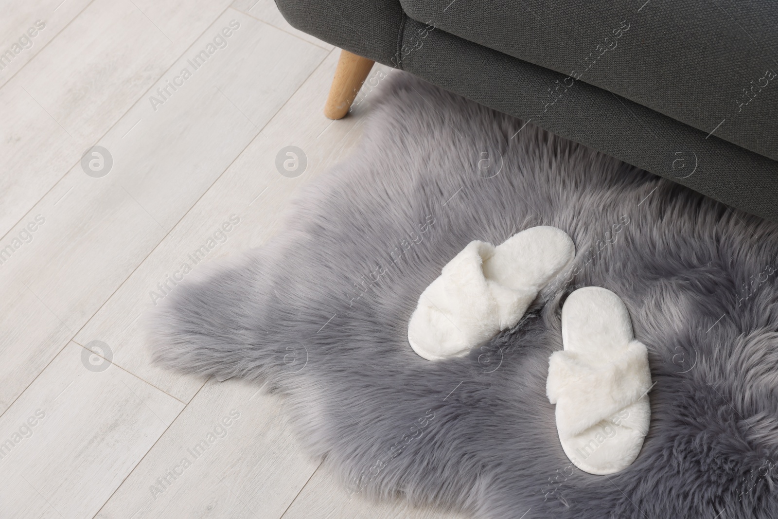 Photo of Faux fur rug with slippers on floor in room, space for text