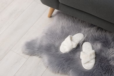 Photo of Faux fur rug with slippers on floor in room, space for text