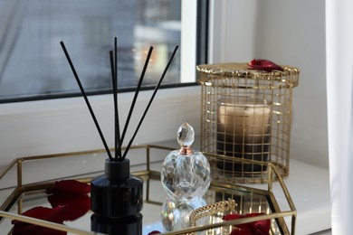 Photo of Aromatic reed air freshener, perfume and rose petals on windowsill