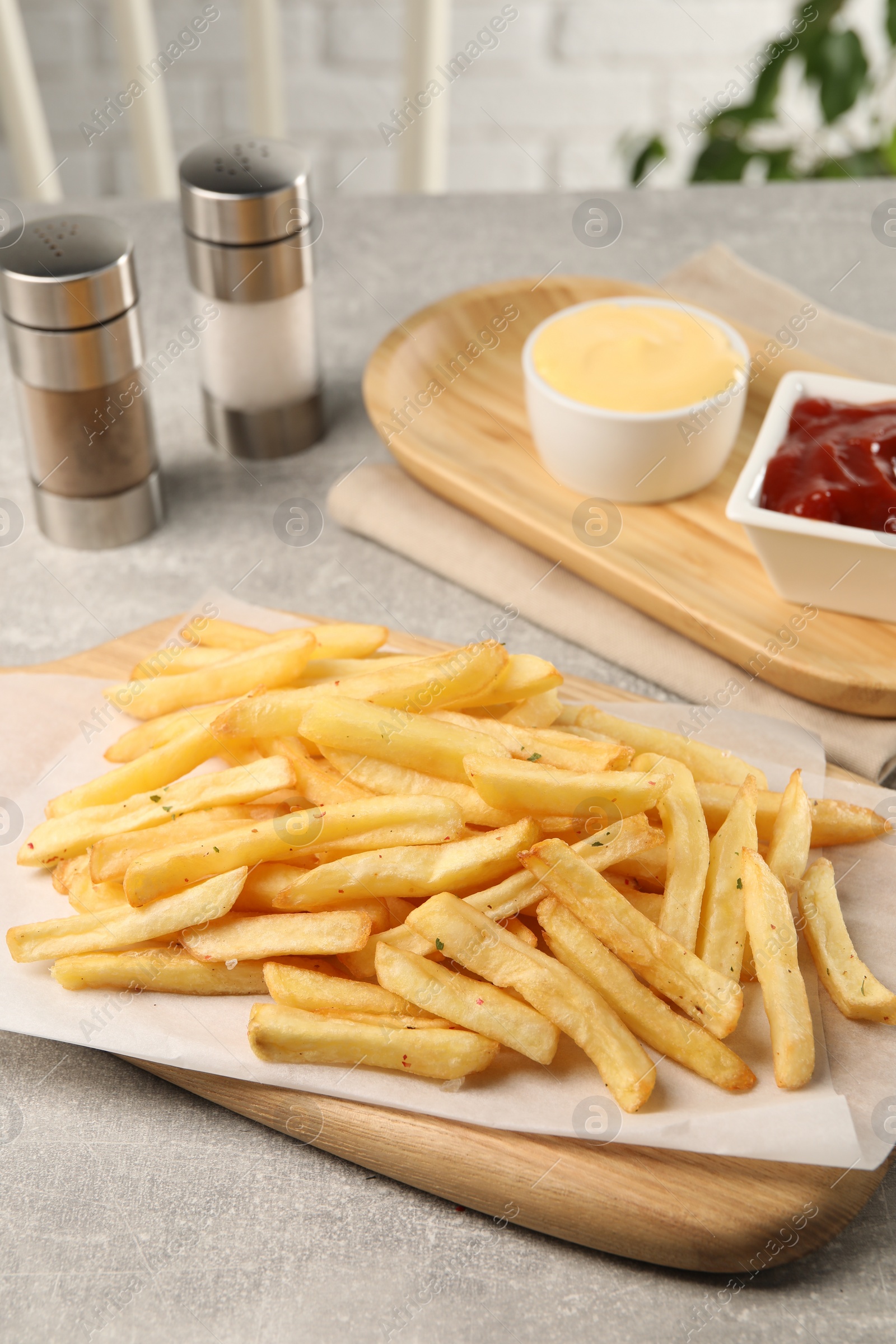 Photo of Delicious french fries served with sauces on light grey table