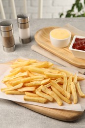 Delicious french fries served with sauces on light grey table
