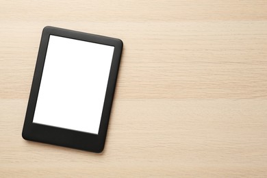Photo of Modern e-book reader with blank screen on wooden table, top view. Space for text