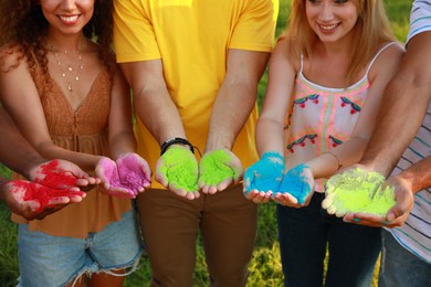 Photo of Friends with colorful powder dyes outdoors, closeup. Holi festival celebration