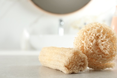 Photo of Natural loofah sponges on table in bathroom, closeup. Space for text