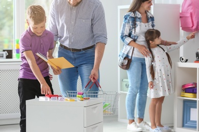 Cute boy with father choosing school stationery in store