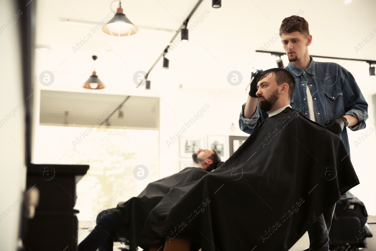 Photo of Professional barber working with client in hairdressing salon. Hipster fashion