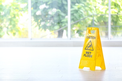 Photo of Safety sign with phrase Caution wet floor, indoors. Cleaning service