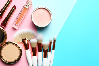 Flat lay composition with professional makeup brushes and different decorative cosmetics on color background. Space for text