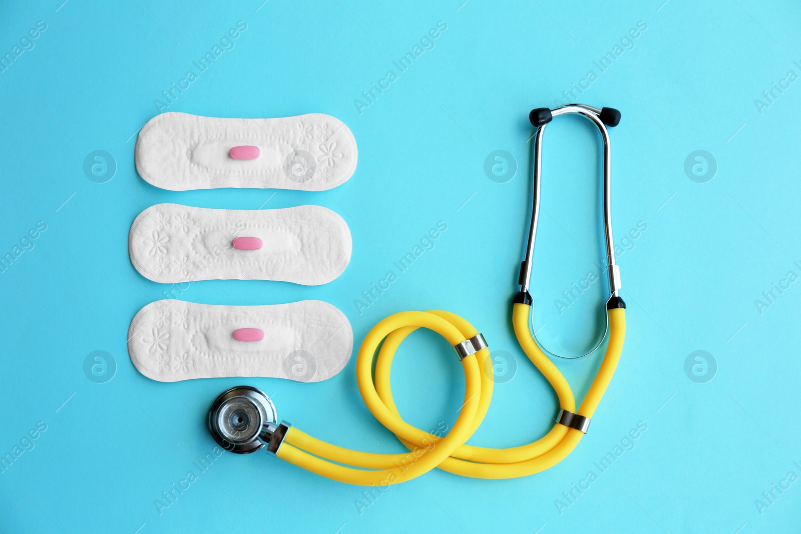 Photo of Flat lay composition with menstrual pads, stethoscope and pills on color background. Gynecological care