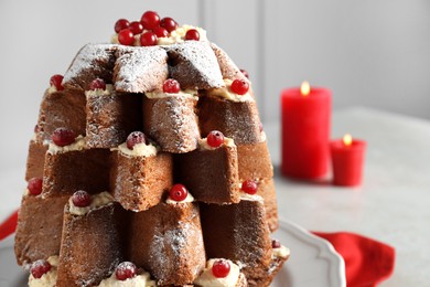 Photo of Delicious Pandoro Christmas tree cake with powdered sugar and berries near festive decor on white table, closeup. Space for text