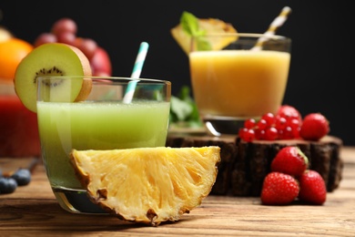 Photo of Delicious colorful juice in glass and fresh ingredients on wooden table, closeup