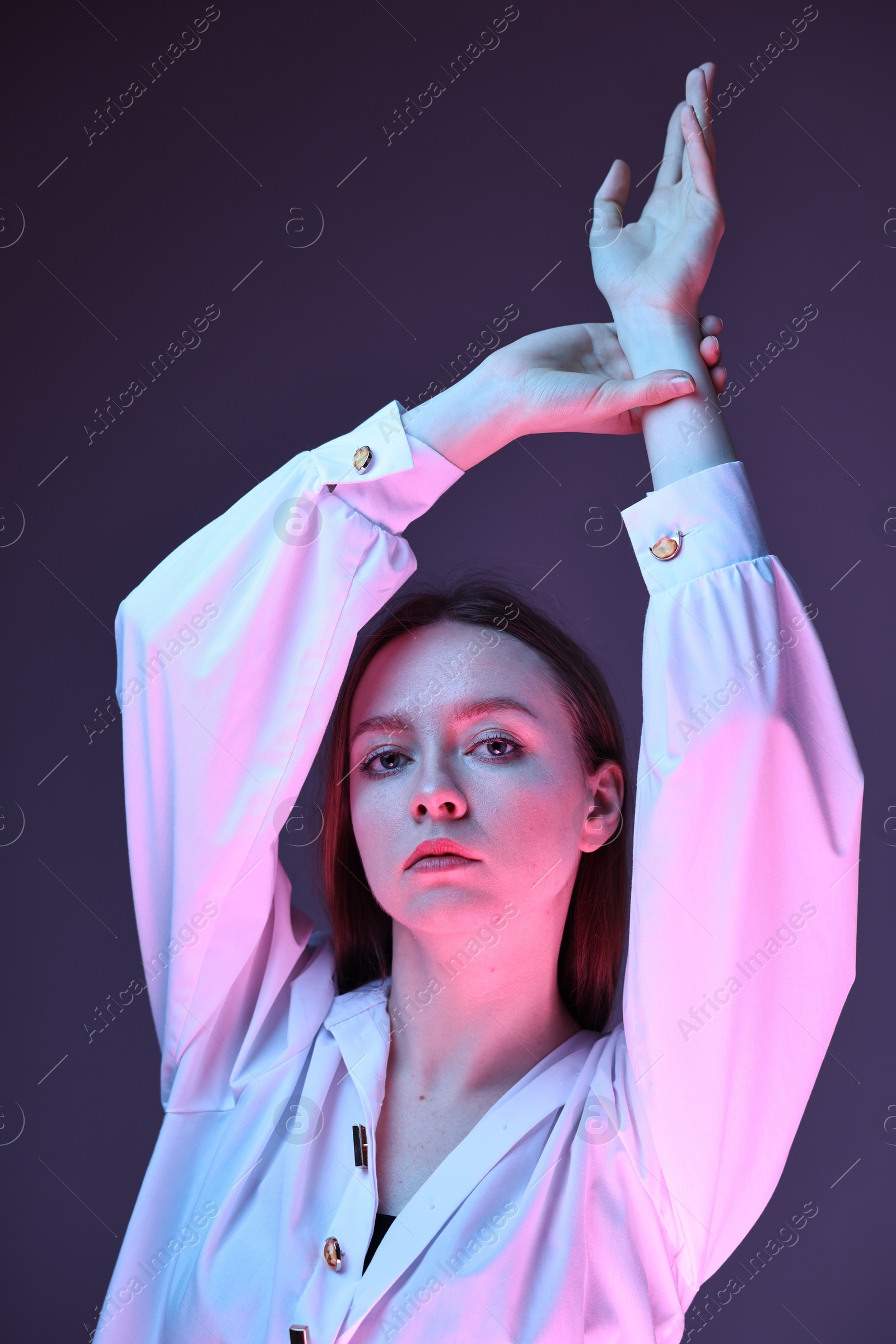 Photo of Fashionable portrait of beautiful young woman on purple background in neon lights