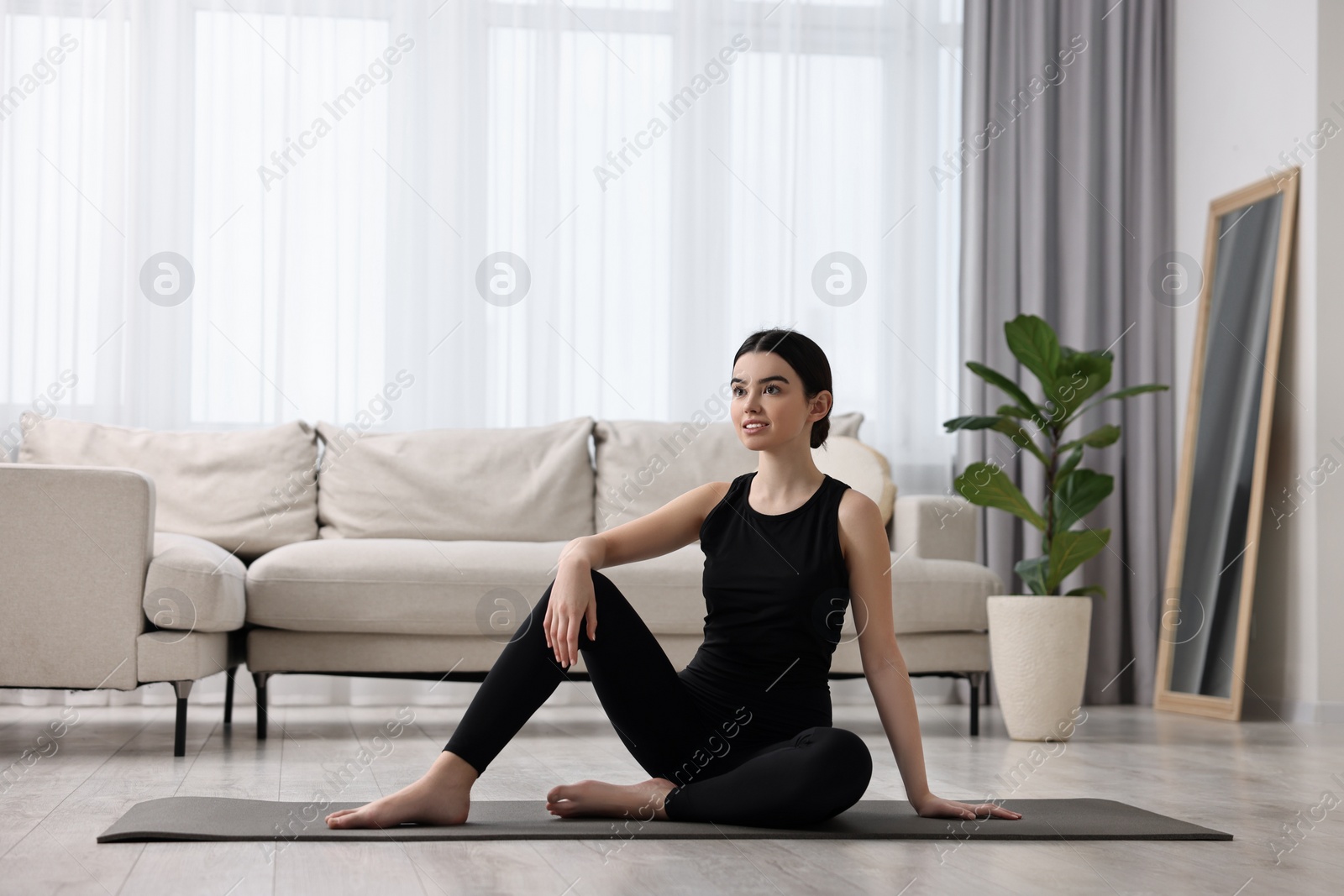 Photo of Beautiful girl sitting on yoga mat at home