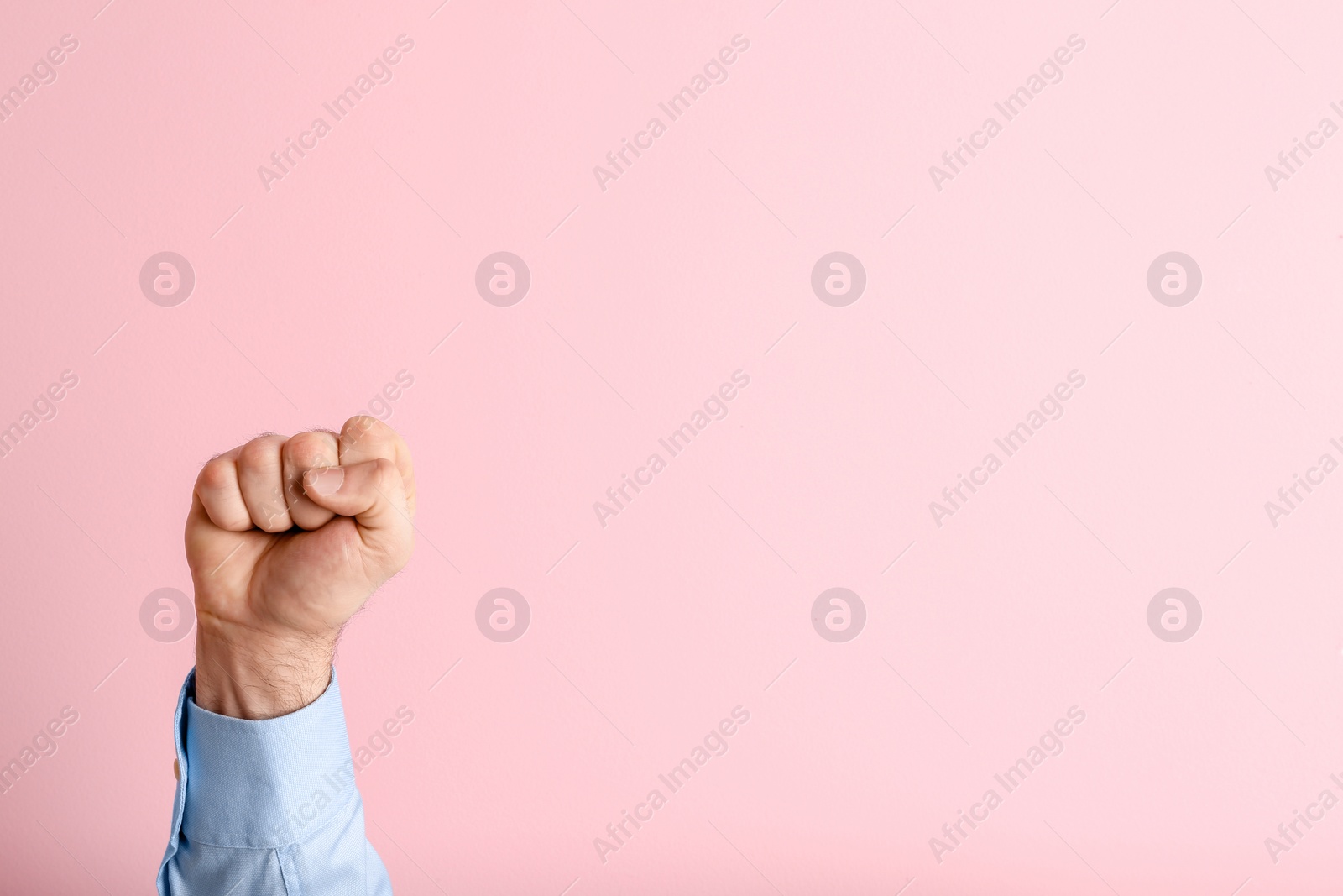 Photo of Young man showing clenched fist on color background. Space for text