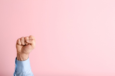 Young man showing clenched fist on color background. Space for text