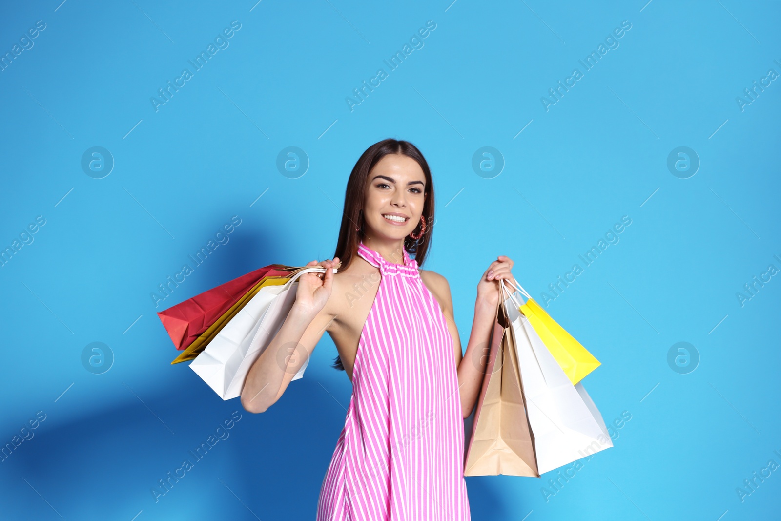 Photo of Young woman with shopping bags on color background