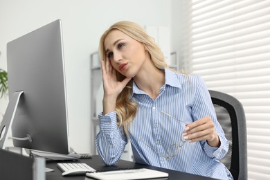 Overwhelmed woman with glasses at table in office