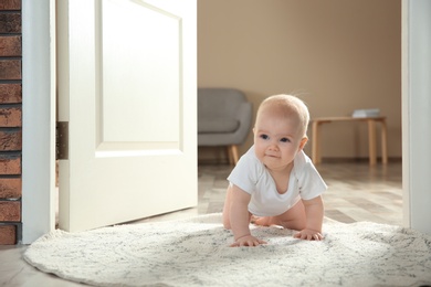 Photo of Cute little baby crawling on rug indoors, space for text