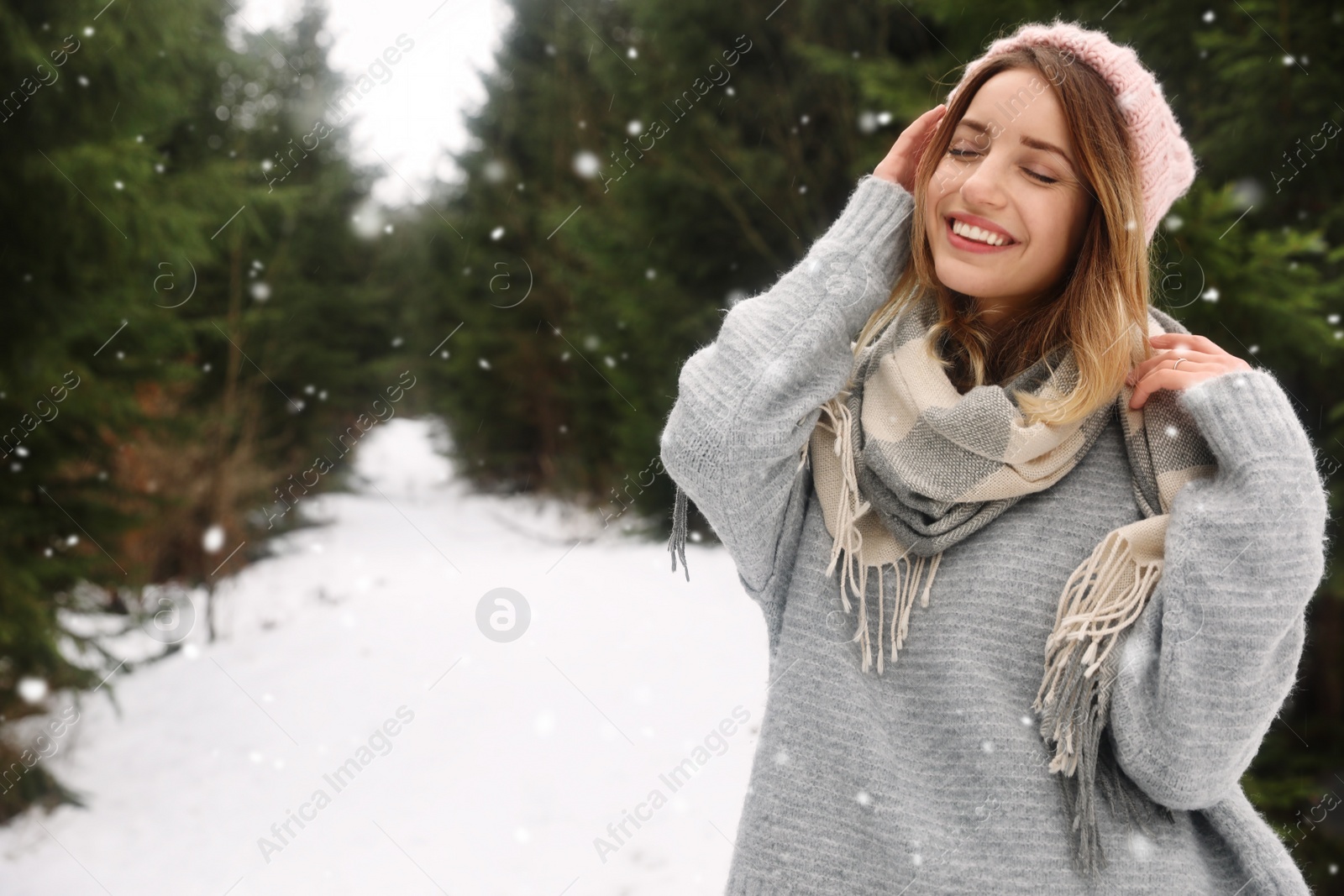 Photo of Young woman in snowy conifer forest, space for text. Winter vacation