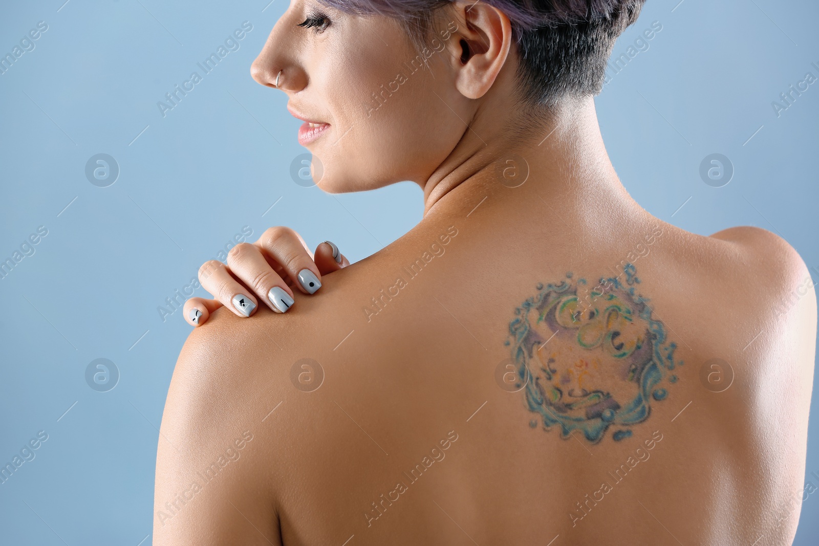 Photo of Beautiful tattoo on female back against color background