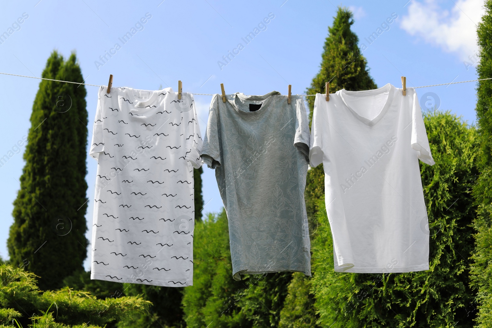 Photo of Washing line with clean clothes in garden. Drying laundry outside