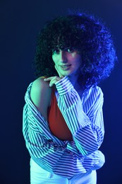 Photo of Beautiful young woman posing on color background in neon lights