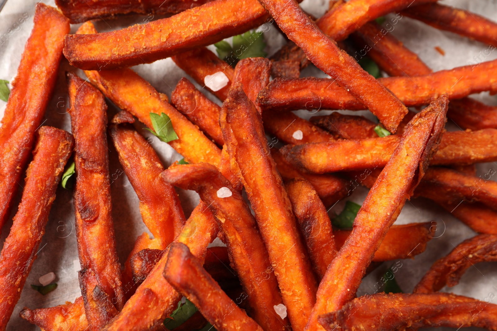 Photo of Delicious sweet potato fries on parchment paper, closeup