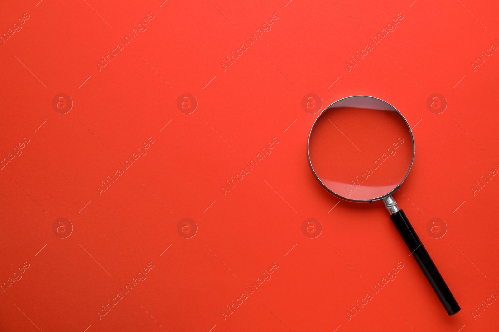 Photo of Magnifying glass on red background, top view. Space for text