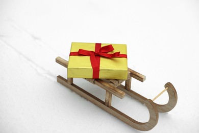 Wooden sleigh with gift box on snow outdoors