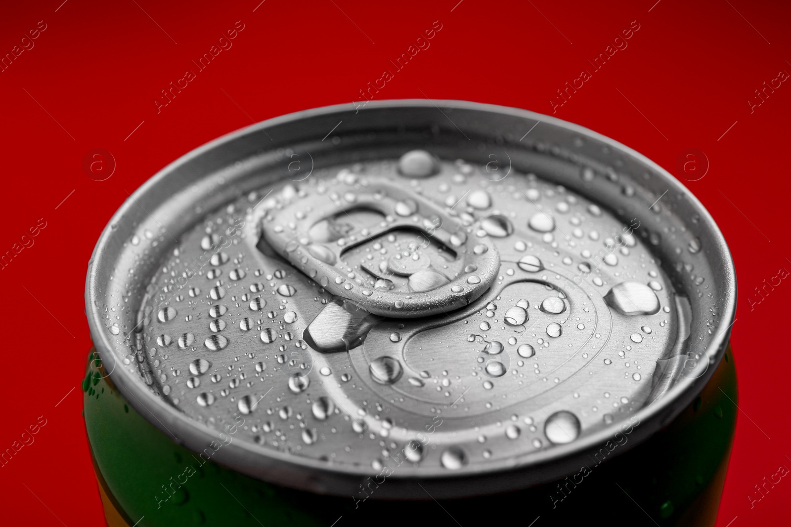Photo of Energy drink in wet can on red background, closeup