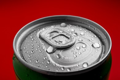 Energy drink in wet can on red background, closeup