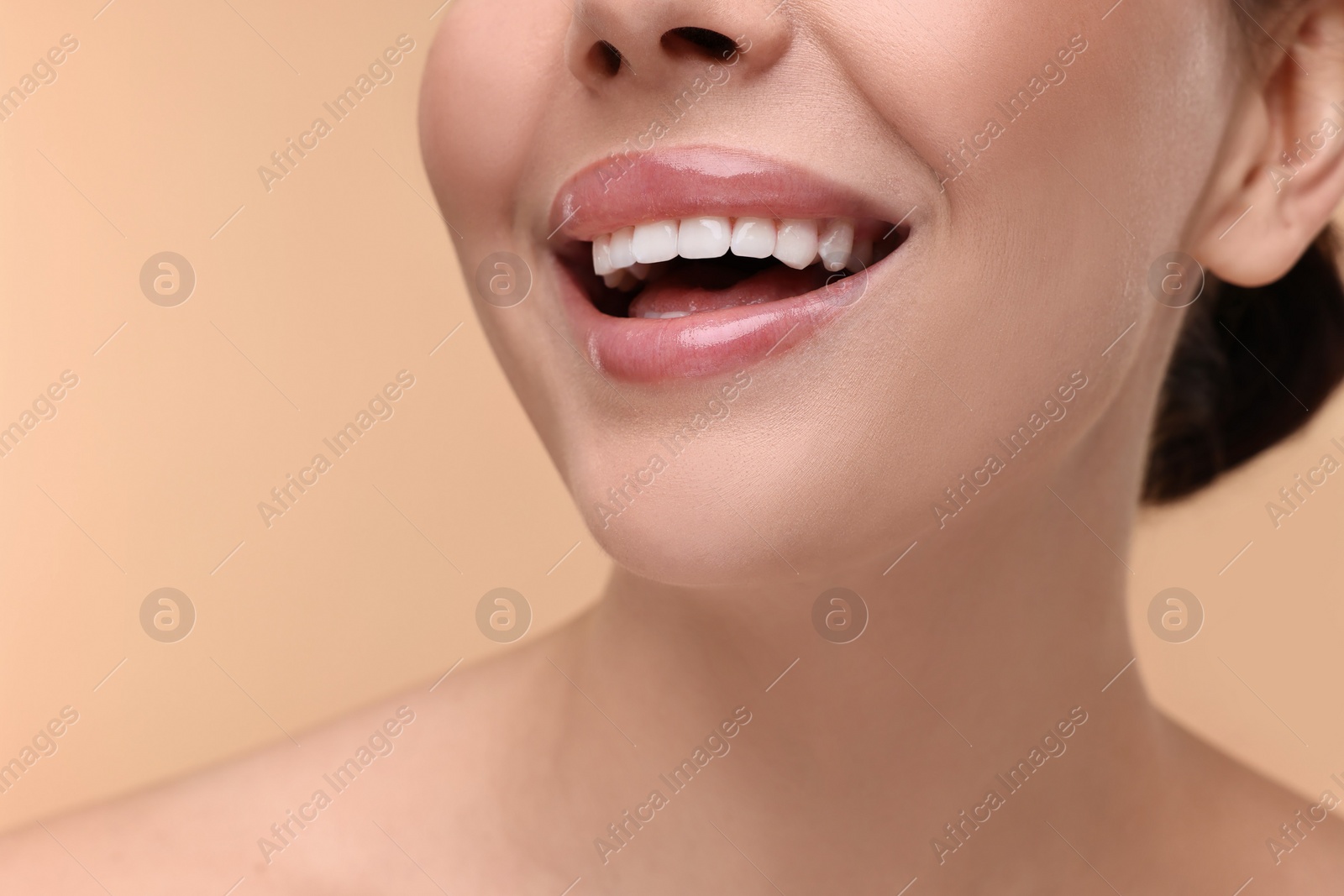 Photo of Woman with beautiful lips smiling on beige background, closeup