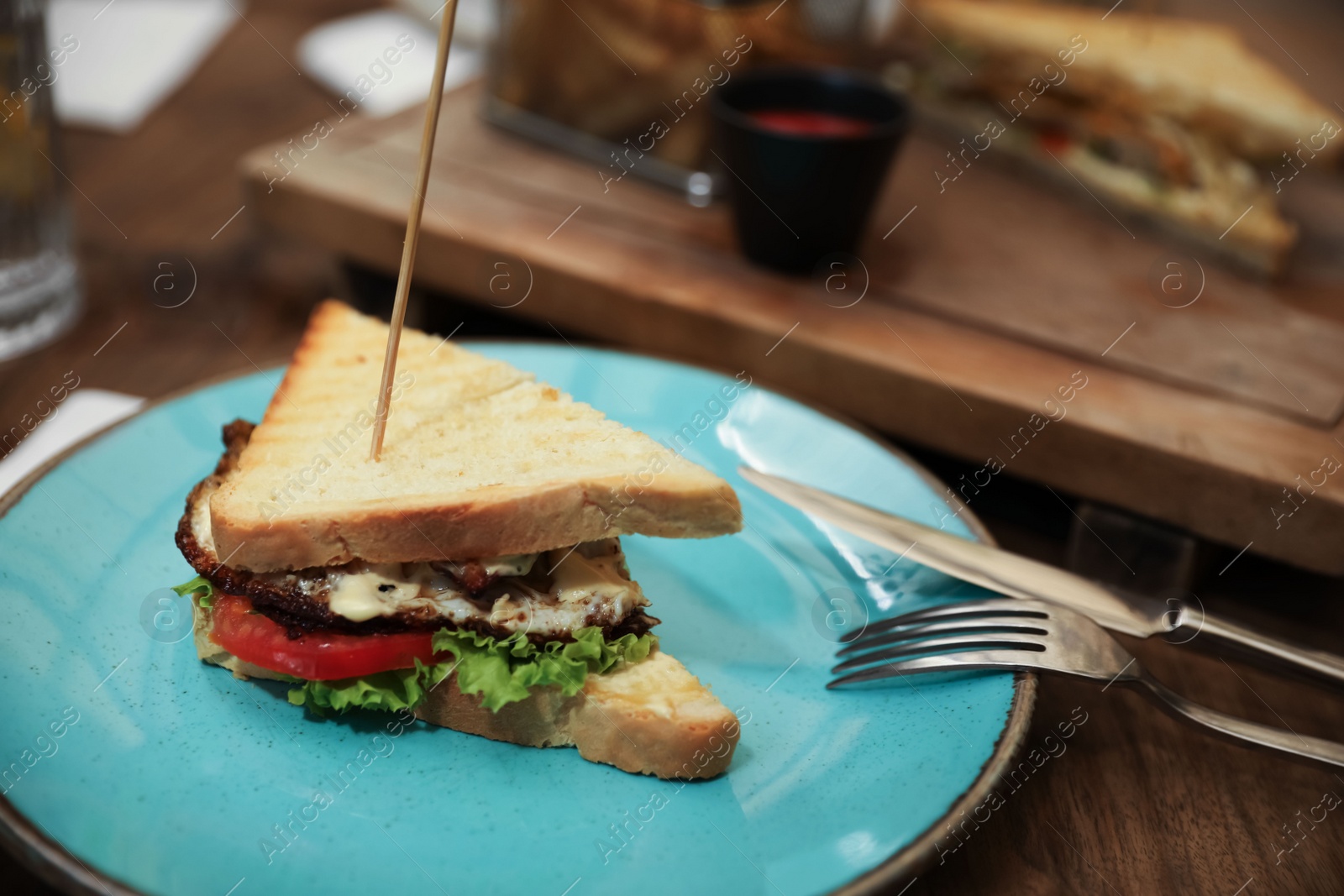 Photo of Delicious sandwich served on wooden table in cafe, closeup