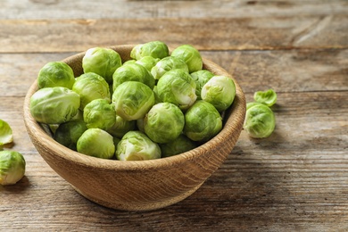 Photo of Bowl of fresh Brussels sprouts on wooden background. Space for text